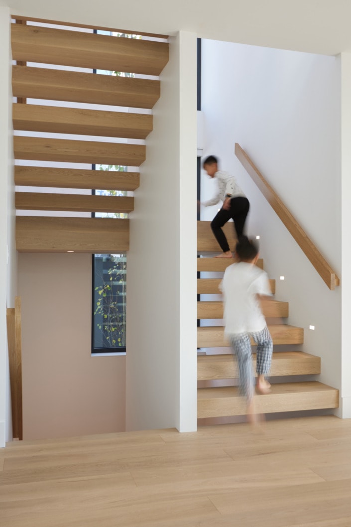 lifestyle architectural interior photo of kids running up residential floating stairs